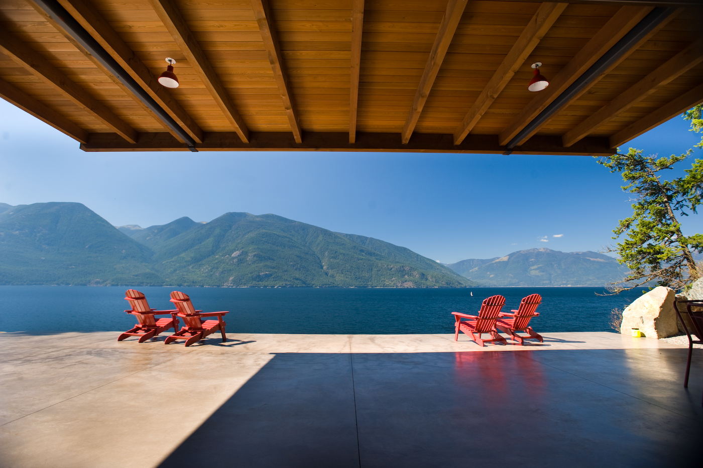 view of the beach from the deck with four lounge chairs