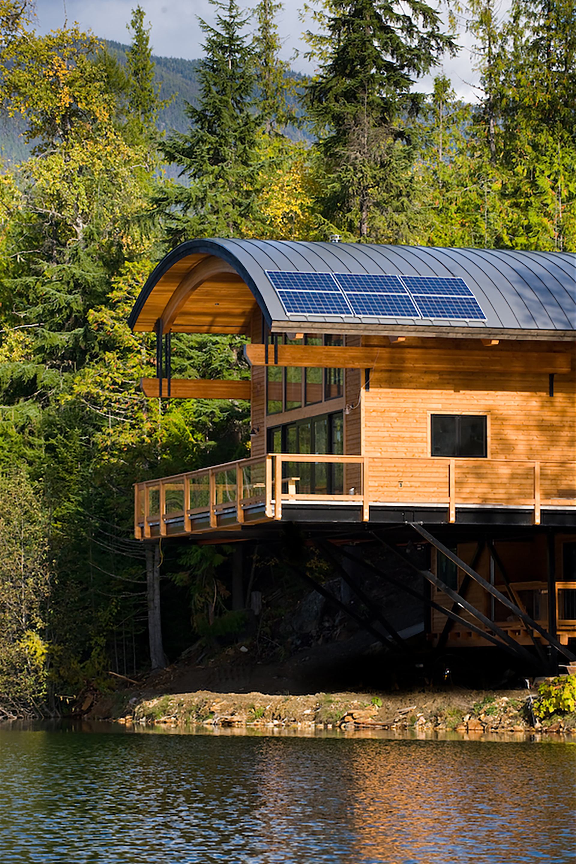 timber-enhanced lakeside house with curved roof and solar panels