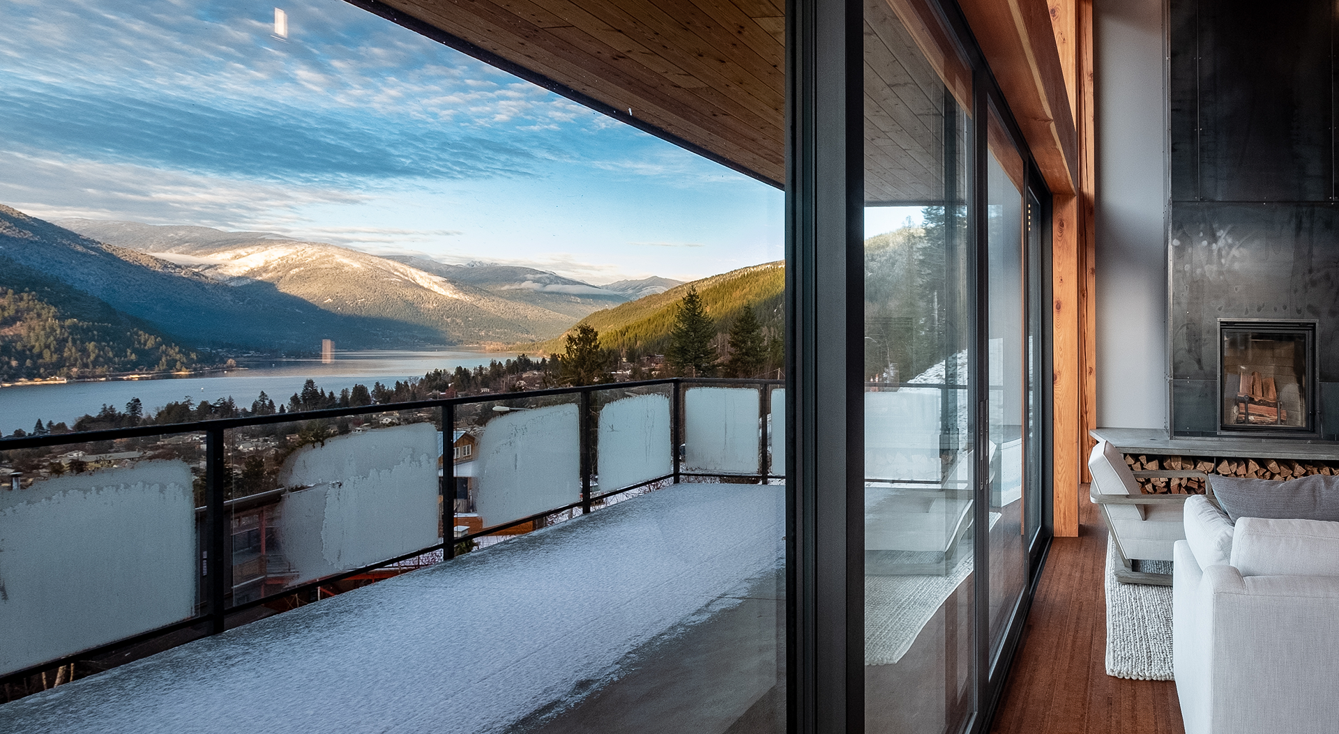 large balcony with snow accumulating on the floor and glass railings